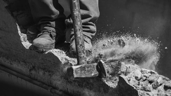 Arbeiter reißt Mauer mit Vorschlaghammer nieder