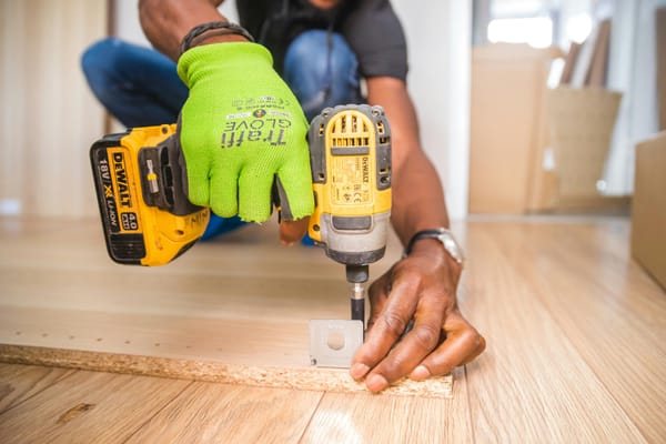 Handwerker schraubt Winkel an Brett